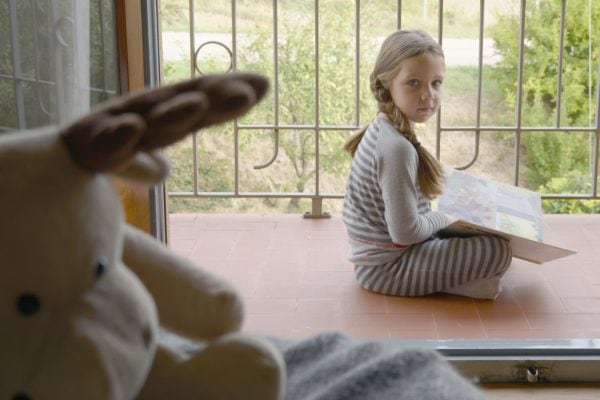 niña leyendo en terraza con su pijama de rayas LOHE