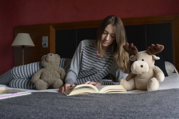 niña leyendo un libro en pijama en su habitación