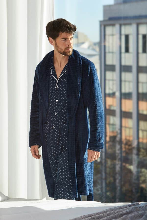 Homewear hombre de invierno 2 Hombre con bata azul marino y pijama estampado junto a una ventana